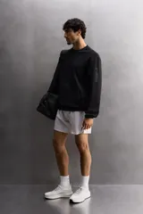 Shorts deportivos color verde oliva confeccionados en tejido técnico ligero y elástico. Cuenta con forro interior, cintura elástica ajustable con cordón, bolsillos laterales, bolsillo de seguridad en espalda con cierre de cremallera, bajo con aberturas laterales y logo estampado en la pierna.