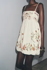 Vestido corto color crudo con tirantes finos ajustables, escote recto y bordado floral a contraste.