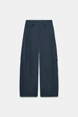 Pantalón cargo de tiro medio color azul oscuro, con pierna ancha y bolsillos de plastrón con solapa en las piernas. Presenta cierre frontal con cremallera, botón y ganchos metálicos.