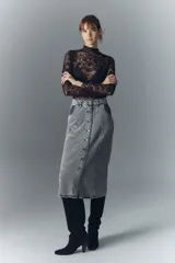 Falda midi de denim rígido con lavado gris, botones metálicos grabados y recortes en el frente.
