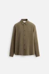Camisa color verde oliva de corte relaxed fit, confeccionada en tejido fluido con mezcla de viscosa. Tiene cuello solapa, manga larga con puño abotonado y cierre frontal con botonadura.