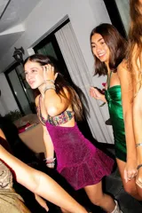 Vestido corto de lentejuelas color verde oliva, con escote en V, breteles finos cruzados en la espalda, cut-outs laterales y volado en el ruedo.