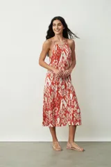 Vestido midi con estampado abstracto en tonos naranja y blanco, breteles finos y corte evasé.