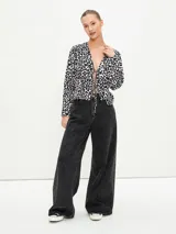Blusa negra con estampado animal print en blanco y marrón, escote en V con lazo ajustable y mangas largas acampanadas.