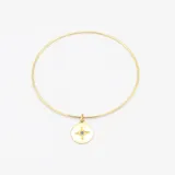 Set de tres pulseras doradas: una rígida con dije redondo con una circonia azul, una rígida lisa y una de cadena de eslabones.