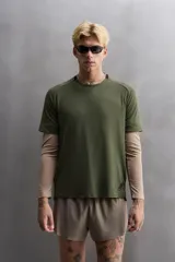 Camiseta deportiva verde militar confeccionada en tejido estructurado, ligero y elástico. Tiene cuello redondo, manga corta y bajo con aberturas laterales. Incluye logo estampado en el bajo.