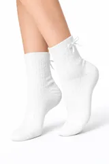 Medias blancas de algodón con diseño de punto trenzado y acanalado. Presentan un pequeño lazo decorativo en la parte superior trasera del caño.