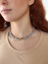 Juego de dos collares cortos de cuentas de piedra en tonos celeste, naranja y dorado.