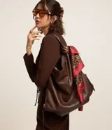 Bolso hobo grande desestructurado de PU color negro, con correa de mano, correa larga desmontable, cierre lateral ajustable con tiradores y cierre superior.