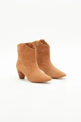 Bota corta de gamuza color camel, estilo cowboy, con taco medio de madera y recortes grabados en forma de mariposa en los laterales.