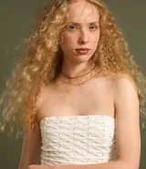 Blusa cropped sin breteles color blanco con pequeños apliques dorados.