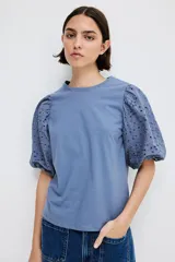 Top azul de punto de algodón con cuello redondo y bajo recto. Mangas globo cortas en tejido de algodón con forro de punto y ribete elástico.