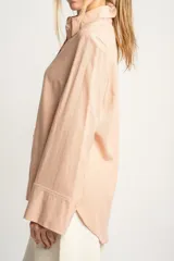 Camisa color salmón de corte oversize, confeccionada en lino y viscosa, con cuello clásico, cierre frontal con botones y mangas largas con puños anchos.
