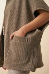 Chaleco color crema de lana sin teñir, corte recto, con cuello y solapa pronunciadas, broches a presión y bolsillos ojal.