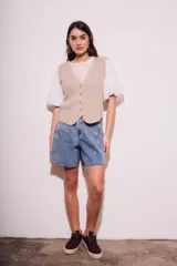 Chaleco de punto color beige con cuello en V y cierre frontal con botones.