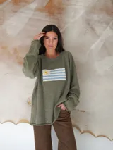 Sweater beige de hilo de algodón con cuello redondo y manga larga. Estampado con la bandera de Uruguay en el frente.