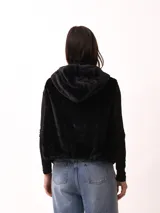 Chaleco negro de textura afelpada o pelo sintético, con cierre frontal.