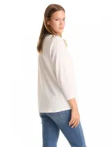 Blusa texturizada color blanco, con cuello a la base y escote en V. Presenta bordados en tonos verdes y blancos alrededor del escote y en el canesú. Mangas 3/4 y tejido suave y elastizado.