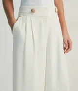 Pantalón pantalona color blanco, de crepé, con cintura mediana, botón y pliegues delanteros.