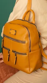 Mochila negra de símil cuero con apertura superior doble con cierres individuales. Bolsillos al frente con cierres metálicos, uno principal de mayor capacidad y dos pequeños. Correas largas a tono regulable con hebillas.