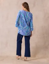 Blusa de gasa estampada con motivos paisley en tonos azules, marca Ruby Rd. Tiene cuello redondo con escote en V y aplique metálico. Presenta una sobre capa delantera y terminación asimétrica. Las mangas son 3/4 y amplias.