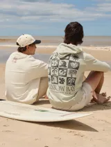 Buzo con capucha color verde claro, con estampado de motivos playeros en la espalda y texto "Rainbow Bay The Goldcoast GEM".