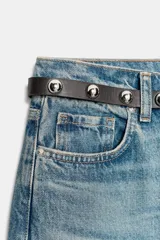 Jeans de tiro alto color azul claro, con cinco bolsillos y pernera recta que se estrecha hacia el tobillo. Incluye un cinturón negro con detalles metálicos.