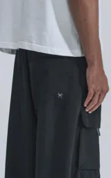 Pantalón cargo negro de corte ancho, con cintura elástica, cinturón con hebilla y múltiples bolsillos.