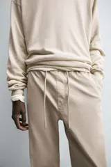 Pantalón jogger negro de corte slim fit, confeccionado en tejido de algodón con cintura elástica ajustable con cordón, bolsillos frontales y traseros de vivo, y bajo con puño elástico.