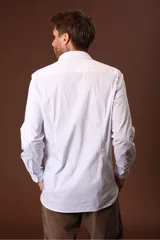 Camisa blanca de manga larga con cuello clásico y cierre frontal con botones.