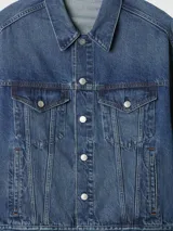 Campera de jean azul con cuello clásico, cierre frontal con botones metálicos y bolsillos con solapa en el pecho.