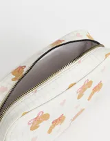 Cartuchera de poliuretano estampada con diseño de croissants y corazones sobre fondo cuadriculado. Incluye tiracierre metálico en forma de croissant y etiqueta roja con logo de la marca.