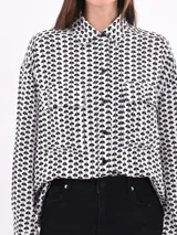 Camisa blanca estampada con motivos geométricos negros, de corte holgado, manga larga y cuello camisero.