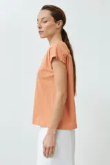 Remera color durazno con cuello en V y detalle de trenza en el escote.