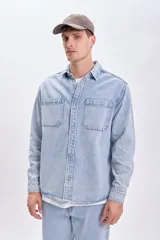 Sobrecamisa de jean celeste con dos bolsillos frontales con solapa y cierre abotonado.