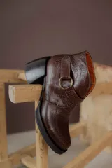 Botas cortas de cuero negro con textura tipo cocodrilo, caña alta, cierre con hebilla y taco de madera.