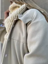 Tapado color beige con cuello solapa, corte recto, largo hasta la rodilla y cinturón de lazo.