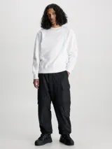 Buzo blanco de felpa de algodón con cuello redondo, puños y bajo acanalados. Estampado vertical con el logo de Calvin Klein Jeans en celeste en el lateral.