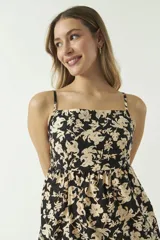 Vestido corto con estampado de orquídeas color beige sobre fondo negro, con breteles finos y corte evasé.