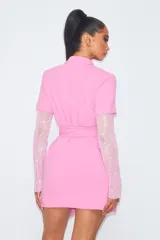 Vestido corto tipo blazer color rosa, con escote cruzado, cinturón y mangas largas de strass.