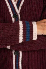 Cardigan de lana color bordó con cuello V y botones frontales. Presenta ribetes en el cuello, puños y ruedo con rayas en color beige y azul marino. Posee dos bolsillos frontales.