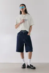 Remera blanca de algodón con cuello redondo y corte holgado. Estampa azul con la palabra 'SYNTHESIS' y texto inferior.
