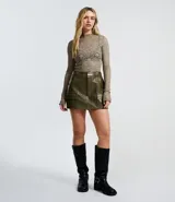 Short pollera corto color verde militar, confeccionado en poliuretano (PU) que imita el cuero. Presenta bolsillos delanteros grandes con solapas, pasadores en la cintura y cierre de cremallera.