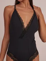 Body negro de tirantes finos con escote profundo en V y detalles de encaje en el escote y los bordes de la pierna.
