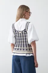 Top tejido sin mangas con diseño geométrico de rombos en relieve, en tonos azul marino y beige. Presenta escote amplio y breteles tejidos.