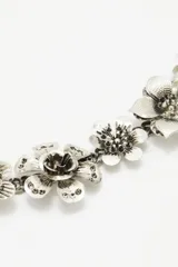 Cinturón plateado de metal con cadena de eslabones y apliques de flores.
