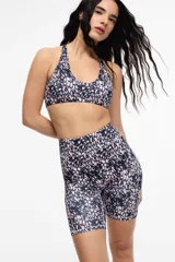 Top deportivo con estampado animal print en tonos rosa y negro, con cuello halter y espalda deportiva.