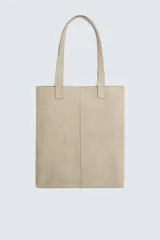 Bolso tipo shopper color beige, fabricado en piel con acabado serraje. Tiene dos asas de mano de piel y un compartimento principal sin cierre con un bolsillo interior con cremallera.