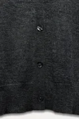 Chaqueta de punto fino color gris oscuro confeccionada con lana. Tiene cuello redondo, manga larga y cierre frontal con botones.