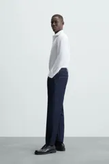 Camisa negra de manga larga con cuello italiano y cierre frontal de botonadura. Presenta un tejido con estructura de fácil cuidado.